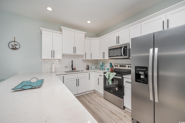 503 30th Ave N, Myrtle Beach, SC 29577 - kitchen featuring appliances with stainless steel finishes, a sink, light wood finished floors, decorative backsplash, and white cabinets