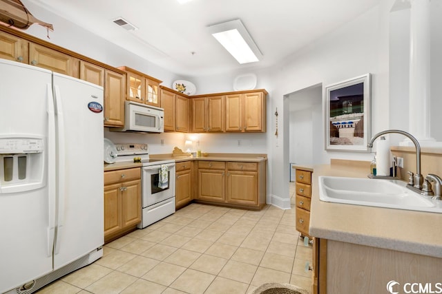 kitchen featuring white appliances, sink, and light tile floors