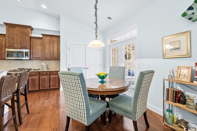 dining space featuring dark hardwood / wood-style floors, french doors, and lofted ceiling