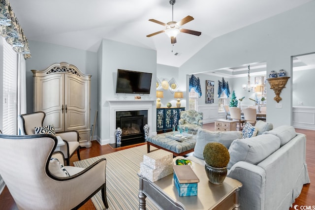 living room with ceiling fan with notable chandelier, vaulted ceiling, dark wood-type flooring, and a wealth of natural light