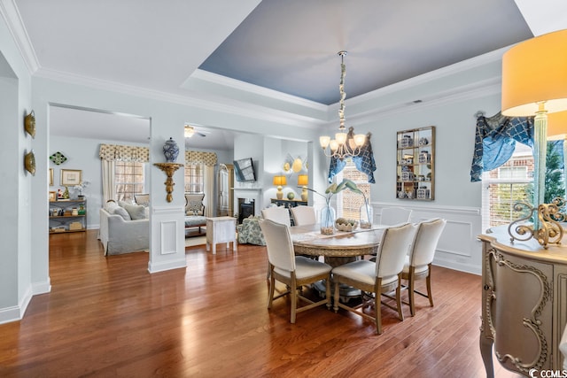 dining space with an inviting chandelier, crown molding, dark wood-type flooring, and a raised ceiling