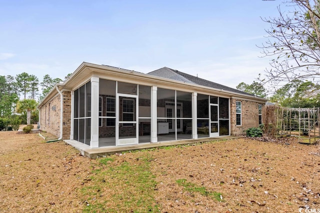 rear view of house with a sunroom, a patio area, and a yard