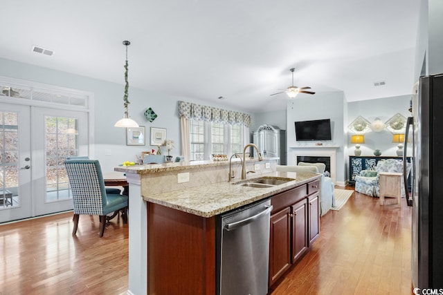 kitchen with hanging light fixtures, stainless steel appliances, a healthy amount of sunlight, and light wood-type flooring