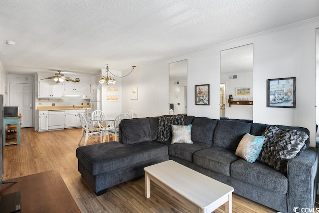 living room with light hardwood / wood-style floors, a textured ceiling, and ceiling fan with notable chandelier