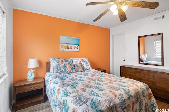 bedroom with wood-type flooring, ceiling fan, and ornamental molding