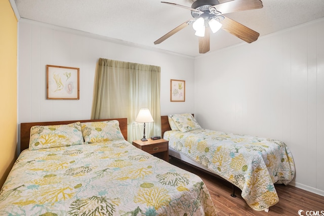 bedroom with crown molding, a textured ceiling, ceiling fan, and dark wood-type flooring