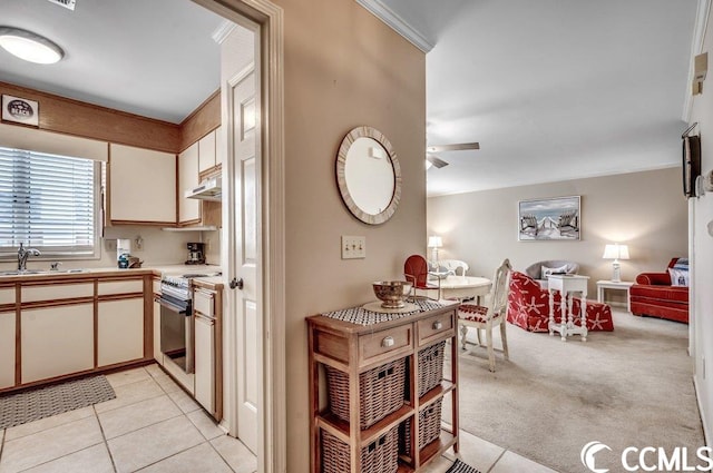 kitchen featuring ceiling fan, stainless steel gas range, sink, crown molding, and light colored carpet