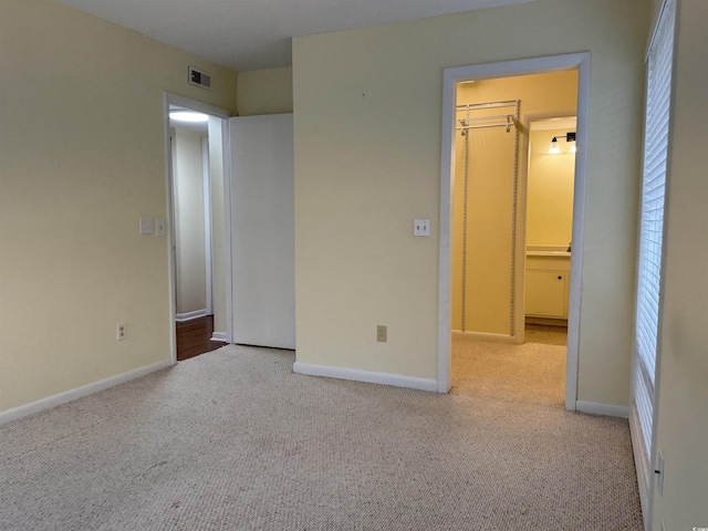 unfurnished bedroom with carpet, visible vents, a spacious closet, and baseboards