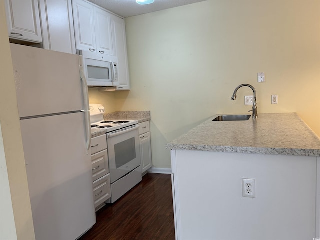kitchen with white cabinets, a sink, dark wood-style flooring, white appliances, and a peninsula