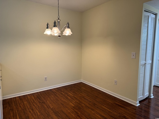 unfurnished room with a chandelier, dark wood-style floors, and baseboards