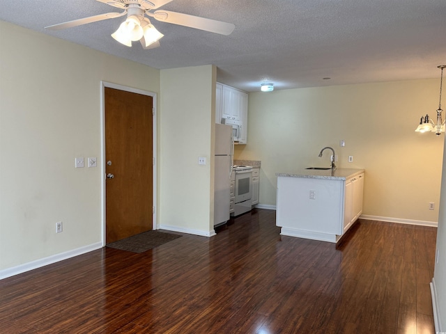 kitchen featuring white cabinetry, a sink, dark wood finished floors, white appliances, and ceiling fan with notable chandelier