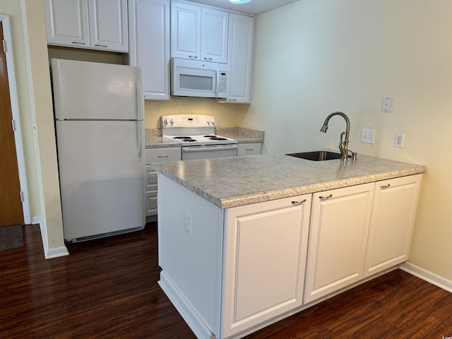 kitchen with white appliances, dark wood-style flooring, a sink, baseboards, and a peninsula