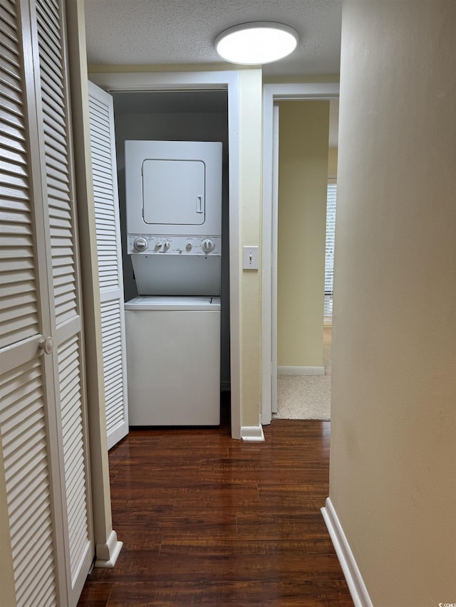 laundry area with stacked washer and dryer, laundry area, dark wood-style floors, and baseboards