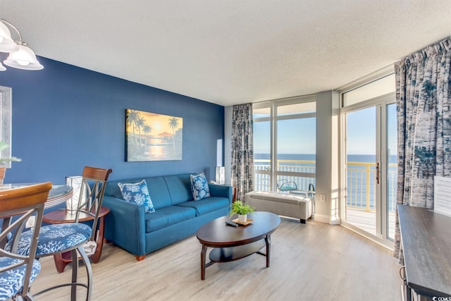 living room with a water view, light hardwood / wood-style floors, and a textured ceiling