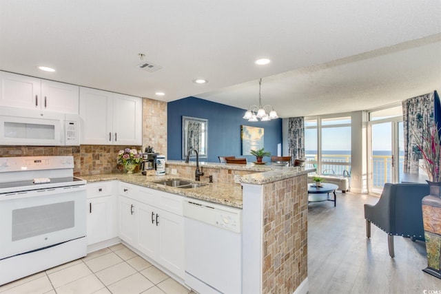 kitchen featuring white appliances, kitchen peninsula, plenty of natural light, and a chandelier