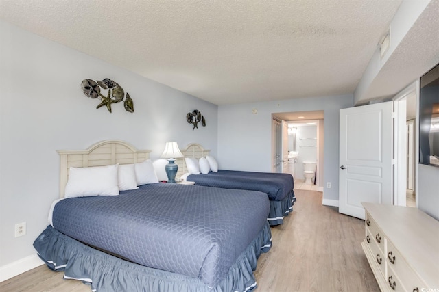 bedroom with ensuite bath, light hardwood / wood-style flooring, and a textured ceiling