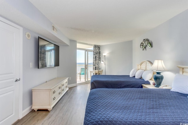 bedroom featuring expansive windows, access to exterior, and hardwood / wood-style flooring