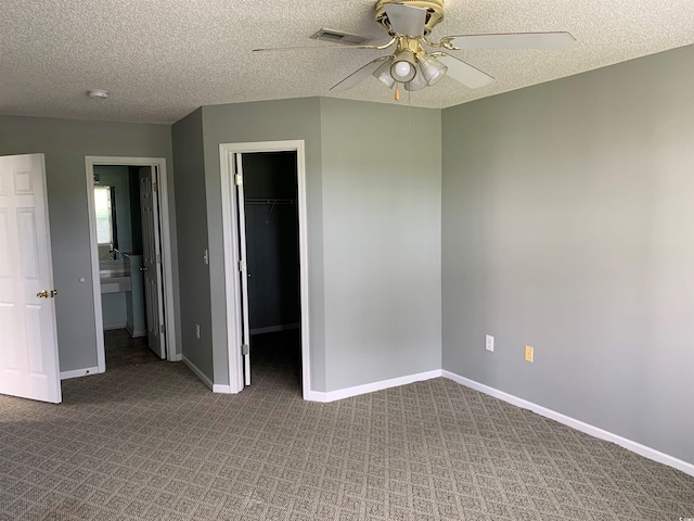 5020 Windsor Green Way Unit 103, Myrtle Beach, SC 29579 - unfurnished bedroom with a walk in closet, carpet flooring, a closet, a textured ceiling, and a ceiling fan