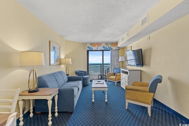 carpeted living room with a water view and a textured ceiling