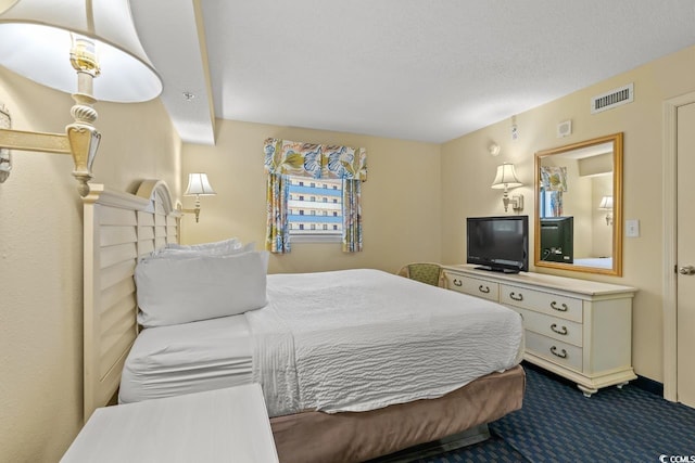 bedroom with dark carpet and a textured ceiling