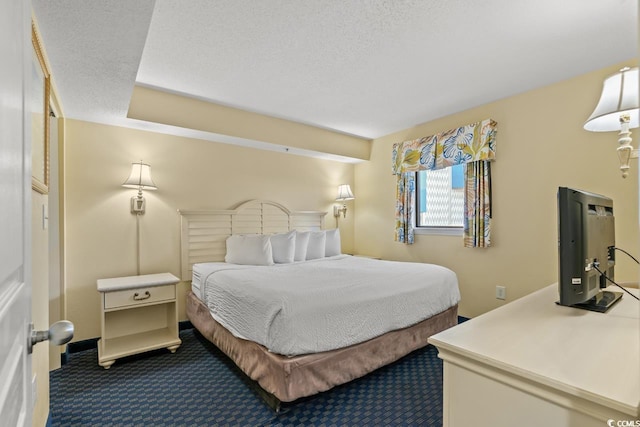 bedroom with dark carpet and a textured ceiling