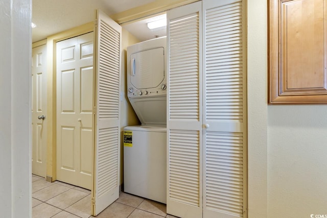 laundry room featuring light tile flooring and stacked washing maching and dryer