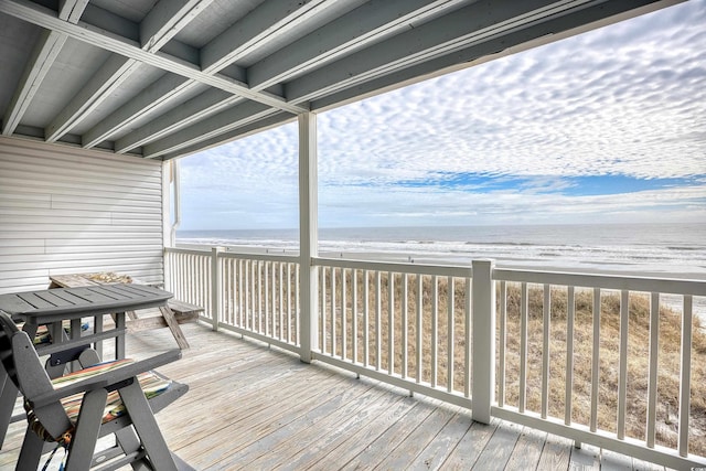 wooden deck with a water view and a view of the beach