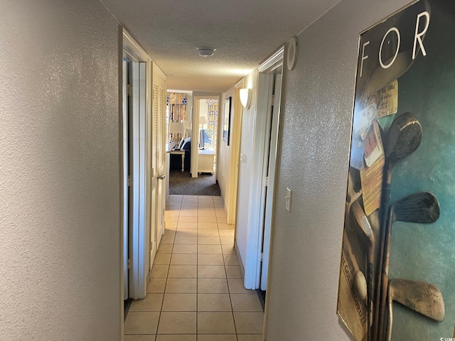 corridor featuring a textured ceiling and light tile floors