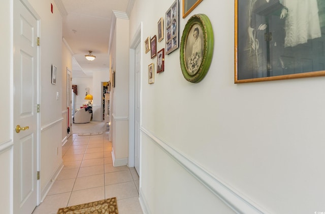 corridor featuring ornamental molding and light tile floors