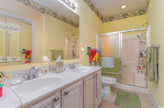 bathroom featuring toilet, a shower with shower door, double sink, large vanity, and tile floors