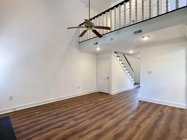 unfurnished living room with ceiling fan, a high ceiling, and dark hardwood / wood-style flooring