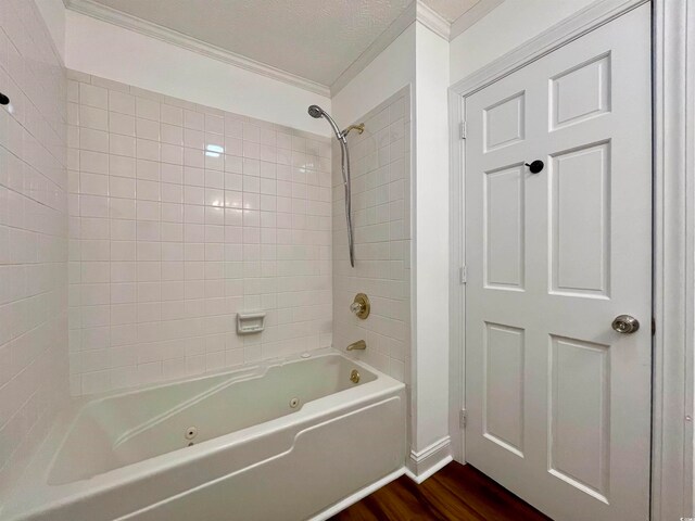 bathroom with tiled shower / bath, a textured ceiling, ornamental molding, and hardwood / wood-style flooring