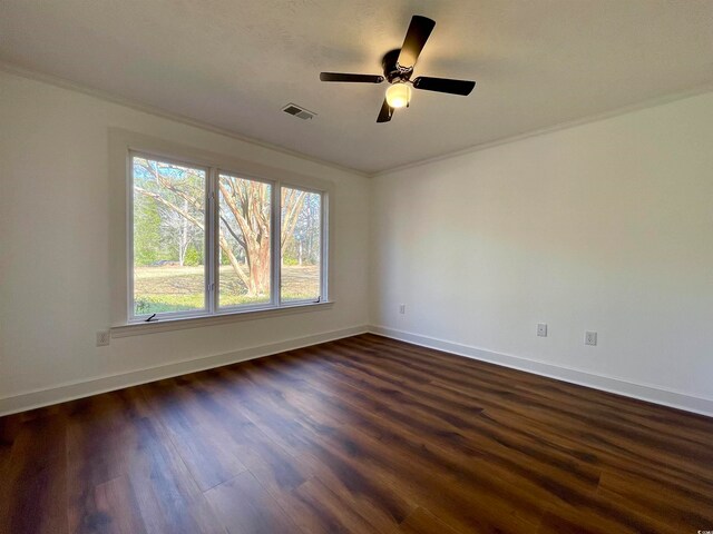 empty room with ceiling fan, dark wood-type flooring, and ornamental molding