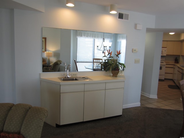 kitchen with hanging light fixtures, white appliances, sink, carpet, and white cabinets