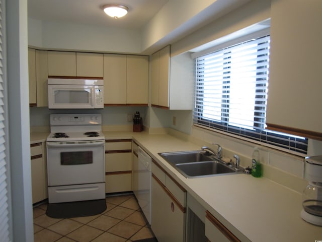 kitchen featuring light tile flooring, white appliances, cream cabinets, and sink