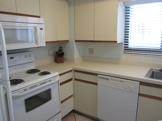 kitchen featuring white appliances, light tile flooring, and white cabinets