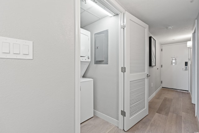 corridor with stacked washer and clothes dryer and light hardwood / wood-style floors