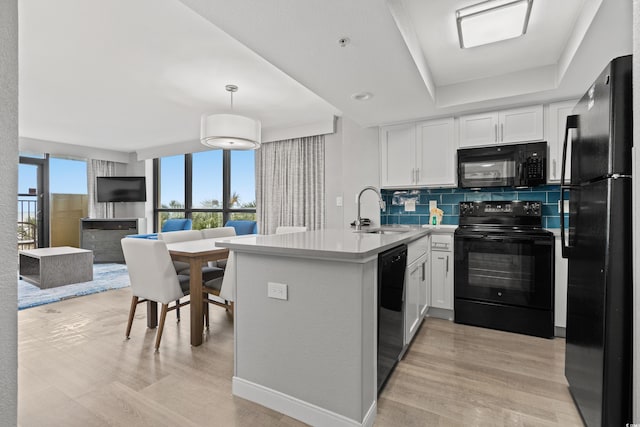 kitchen with decorative light fixtures, tasteful backsplash, white cabinets, black appliances, and sink