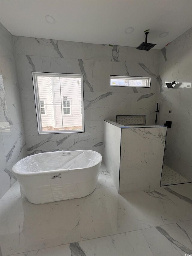 bathroom featuring a soaking tub, stone wall, a healthy amount of sunlight, and a marble finish shower