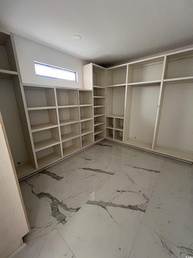 walk in closet featuring marble finish floor