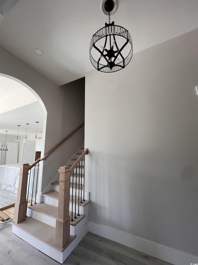 stairway featuring arched walkways, baseboards, and wood finished floors