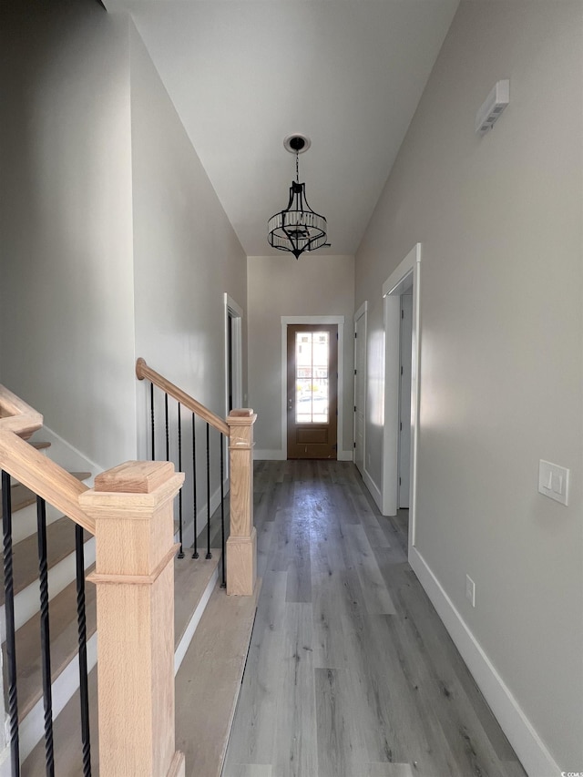 foyer entrance with a chandelier, baseboards, stairs, and light wood-style floors