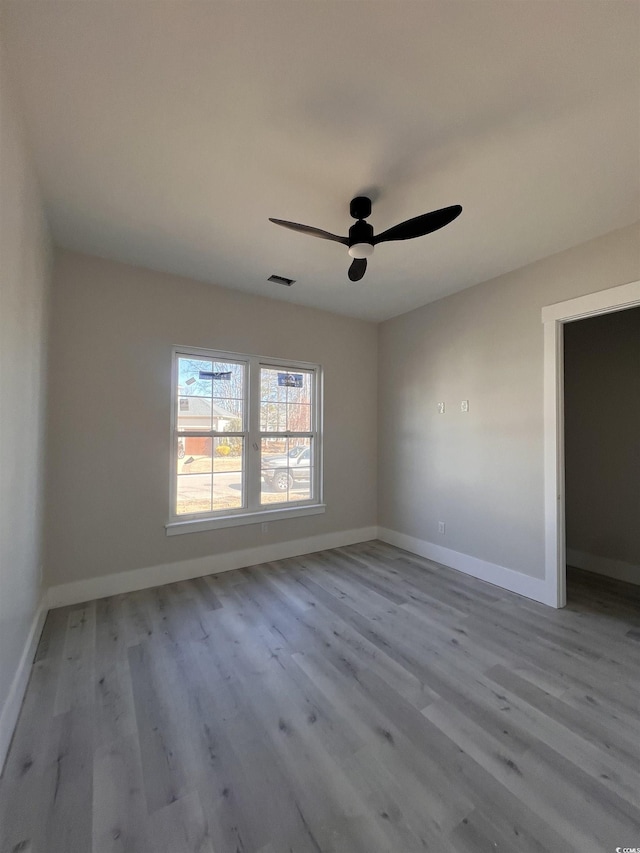 spare room with wood finished floors, visible vents, and baseboards