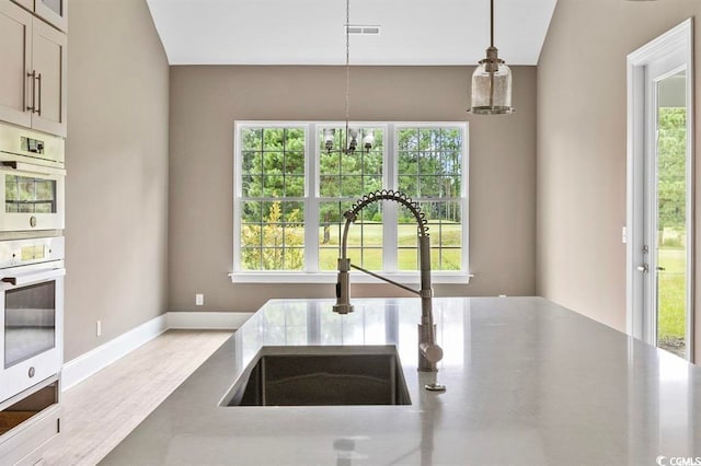 kitchen featuring a sink, visible vents, wood finished floors, and a wealth of natural light