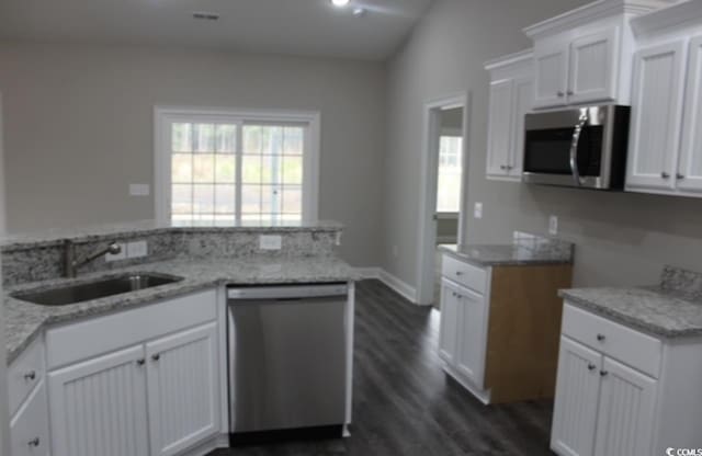 kitchen with a sink, stainless steel appliances, light stone counters, and a wealth of natural light