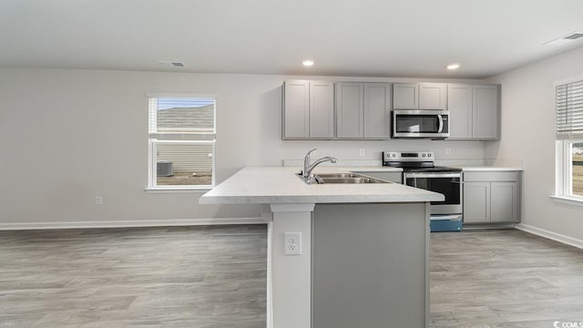 kitchen featuring gray cabinets, light wood-type flooring, kitchen peninsula, and appliances with stainless steel finishes