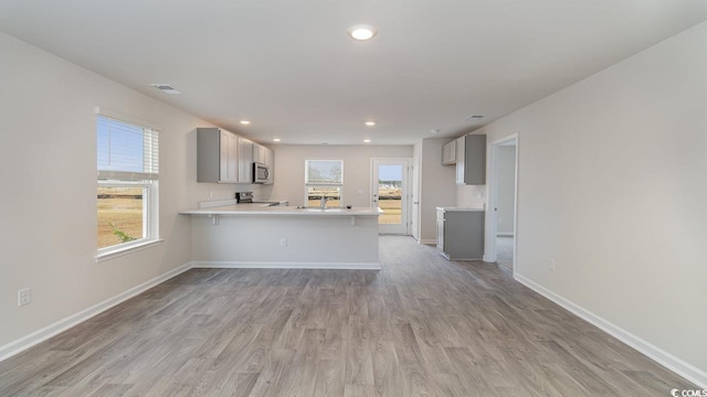 kitchen featuring gray cabinets, appliances with stainless steel finishes, a peninsula, light countertops, and baseboards