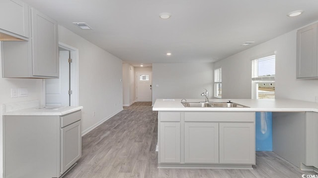 kitchen featuring kitchen peninsula, light hardwood / wood-style floors, gray cabinetry, and sink