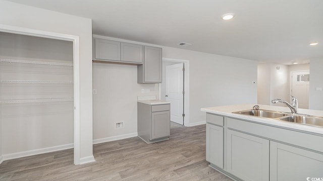 kitchen with gray cabinetry, sink, and light wood-type flooring