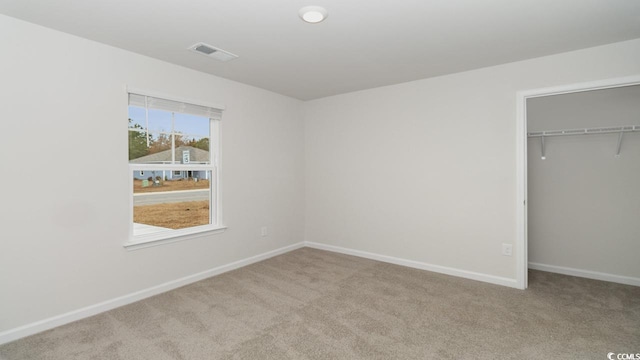 unfurnished bedroom with light colored carpet and a closet